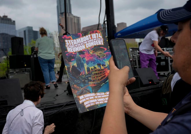 Paul Peña, of Austin, photographs a poster for the Steamboat 1874 Reunion Concert at Auditorium Shores at SXSW Thursday March 14, 2024. The concert featured Austin bands that frequently performed at the Sixth Street venue in the 90s.